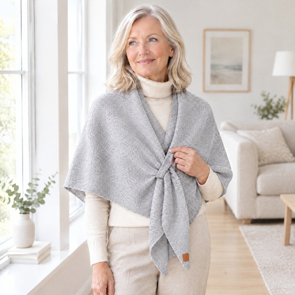 Woman wearing The Loop Shawl in light grey over a cream turtleneck